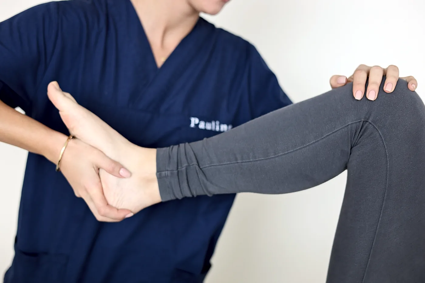 Kinésithérapeute en blouse bleue mobilisant la jambe ou la nuque d’une patiente